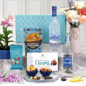 A premium Grey Goose vodka, lemonade, and gourmet confectionery gift hamper presentation.