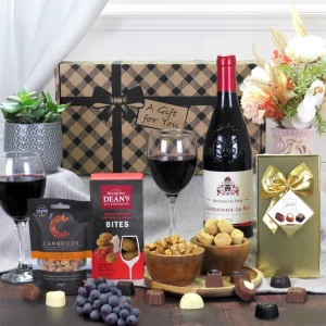 A luxury Châteauneuf-du-Pape red wine, gourmet chocolate, and savory snack gift hamper presentation.