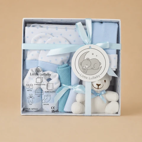 A blue and white "Little Lullaby" 7-piece newborn gift set presented in a white box with a light blue satin ribbon and a small plush teddy bear.