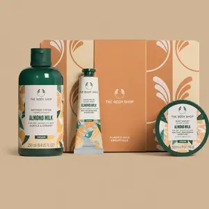 The Body Shop Almond Milk Essentials body care gift set, showcasing three individual almond milk products arranged in front of a tan gift box.