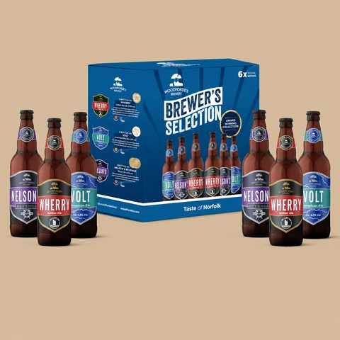 A Woodforde’s Brewery Brewer’s Selection 6-bottle variety gift pack featuring six individual ale bottles flanking a blue presentation box.