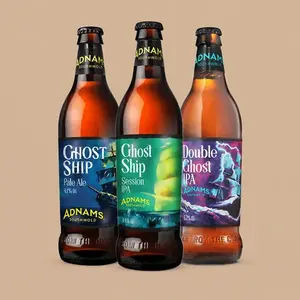 Three brown glass bottles of Adnams Ghost Ship craft beers lined up against a solid light tan background.