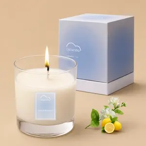 A lit single-wick "ascendia Lemon Blossom" scented candle in a clear glass tumbler, next to its blue gradient packaging box, fresh lemons, and white blossoms.