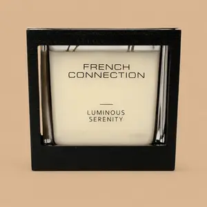A French Connection Luminous Serenity multi-wick glass candle in a black presentation frame.