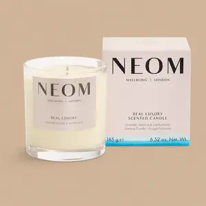 A NEOM Real Luxury lavender, jasmine, and sandalwood jar candle next to its box.