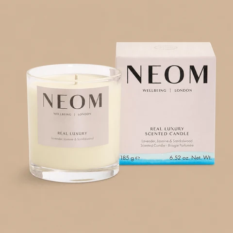A NEOM Real Luxury lavender, jasmine, and sandalwood jar candle next to its box.