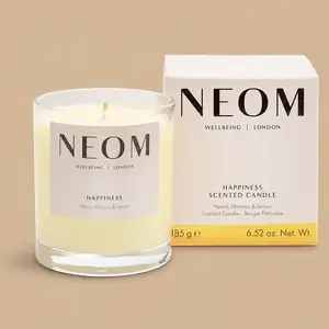 A NEOM Happiness neroli, mimosa, and lemon jar candle next to its product box.