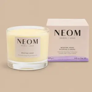 A NEOM Bedtime Hero chamomile, ylang ylang, and cedarwood 3-wick jar candle next to its product box.