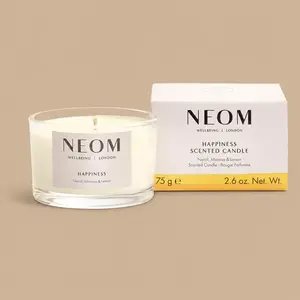 A NEOM Happiness neroli, mimosa, and lemon travel jar candle next to its product box.