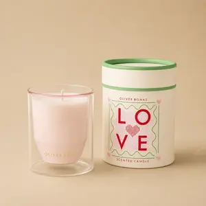 An Oliver Bonas Love double-walled pink jar candle next to its cylindrical packaging.