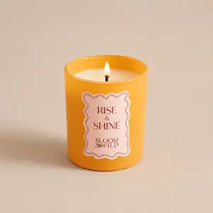 A lit Bloom & Wild Rise & Shine orange jar candle.