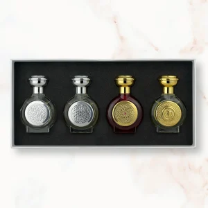 "An open rectangular gift box presenting four miniature, rounded Boadicea the Victorious perfume bottles: two clear glass bottles with silver caps and shields, followed by a dark burgundy bottle and a clear glass bottle with golden caps and shields."