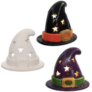 Three ceramic witch hat tealight holders shown side-by-side, featuring star-shaped cutouts that emit a glowing light, displayed in unpainted white, gloss black, and deep purple finishes.