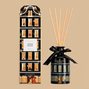 A Cocorrína Cedar Wood reed diffuser set featuring a black townhouse-shaped gift box and matching ceramic diffuser bottle with a black ribbon.
