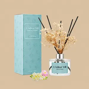 A L'odeur Vill Peony Freesia reed diffuser set featuring a clear glass bottle styled with black reeds, dried florals, and a matching dusty teal gift box.