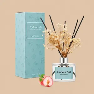 A L'odeur Vill Honey Peach reed diffuser set featuring a clear glass bottle styled with black reeds, dried flowers, and a textured dusty teal gift box.