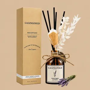 A GAGINGOOLD French Juniper & Lavender reed diffuser set featuring an amber glass bottle styled with a twine bow, black reeds, and dried botanicals next to its kraft paper gift box.
