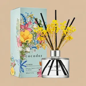 A Cocodor Lemon Eucalyptus reed diffuser set featuring a clear glass bottle styled with black reeds, vibrant yellow baby's breath, and a colorful floral gift box