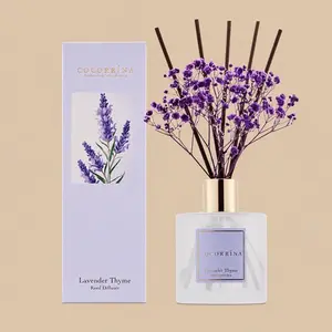 A Cocorrína Lavender Thyme reed diffuser set featuring a frosted glass bottle styled with dark brown reeds, purple baby's breath, and a matching lavender gift box.
