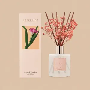 A Cocorrína English Garden reed diffuser set featuring a frosted glass bottle styled with brown reeds, pink baby's breath, and a matching pale pink gift box.