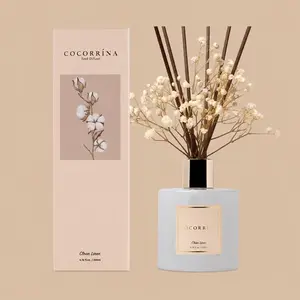 A Cocorrína Clean Linen reed diffuser set featuring a glossy white glass bottle styled with brown reeds, cream-white baby's breath, and a pale taupe gift box.
