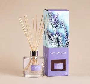 A Wax Lyrical Soft Lavender reed diffuser set featuring a clear glass bottle with light-colored wooden reeds and a pastel purple gift box decorated with an image of fresh lavender stems.