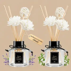 A pair of "Scent Diffuser" clear glass bottles filled with natural wood sticks, decorative white faux flowers, and a rattan ball accent.