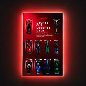 A vertical, wall-mounted LEGO Speed Champions F1 Red Track display frame titled "LIGHTS OUT LEGENDS LIVE" showcasing ten brick-built race cars in a 3x4 grid formation with an intense red integrated ambient backlight.