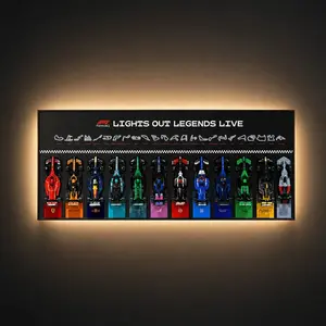 A horizontal, wall-mounted Brick Zone Hub F1 12-Car Display Frame titled "LIGHTS OUT LEGENDS LIVE" showcasing 12 brick-built race cars lined up side-by-side above their team names and branding plaques, enhanced with warm integrated ambient backlighting.