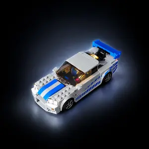 A completed LEGO Speed Champions 2 Fast 2 Furious Nissan Skyline GT-R (R34) model fully illuminated with a custom LED light kit, showcasing glowing headlights against a dark background.