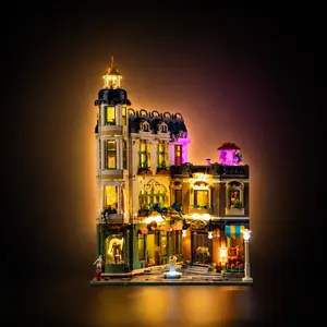 A completed LEGO Icons Shopping Street (11371) modular building set fully illuminated with a custom LED light kit, showcasing glowing multi-story shop windows and street lamps against a dark background.