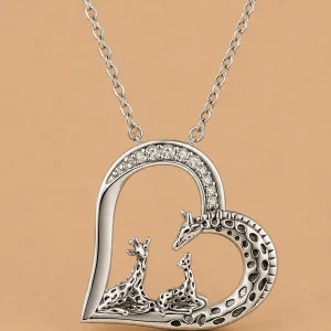 925 sterling silver giraffe family heart necklace. Features an open-heart pendant enclosing a parent and child giraffe design with dark textured spots, accented by small clear crystals along the upper curve over a warm beige background.