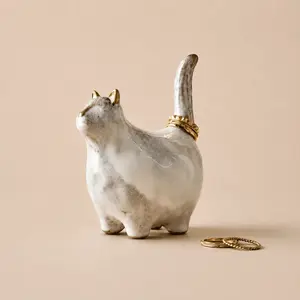 A marbled ceramic cat ring holder displaying gold rings on its tail.