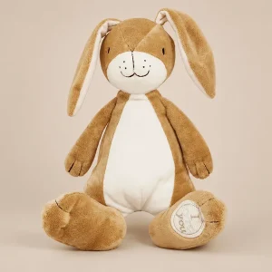 Guess How Much I Love You Nutbrown Hare plush soft toy. Features floppy long ears, a cream-colored belly and muzzle with embroidered facial details, and a stitched "I love you" message on the footpad over a beige backdrop.