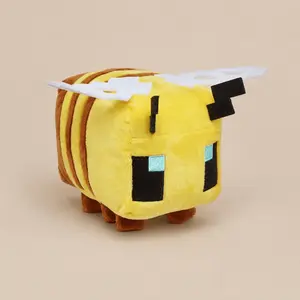 Official Minecraft Bee stuffed plush toy. Features a blocky cuboid yellow and brown striped body, pixelated black and blue embroidered eyes, brown felt antennae, and white pixel-cut wings on a neutral beige background.Example