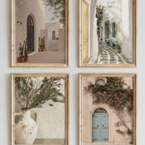 A grid of four vertical light-wood framed art prints hanging on a light grey wall, featuring warm-toned Mediterranean scenes including white buildings, village streets, olive branches, and a rustic archway.