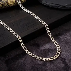 A polished silver Figaro chain necklace featuring alternating small round links and longer oval links, displayed on a dark wood and charcoal plush fabric background.