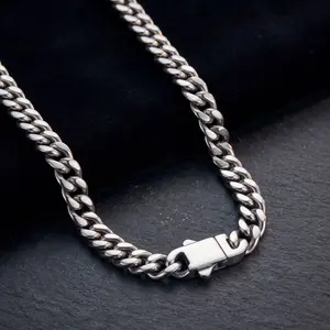 A men's thick silver Cuban link chain necklace featuring a modern rectangle box clasp, displayed on black velvet and dark slate.