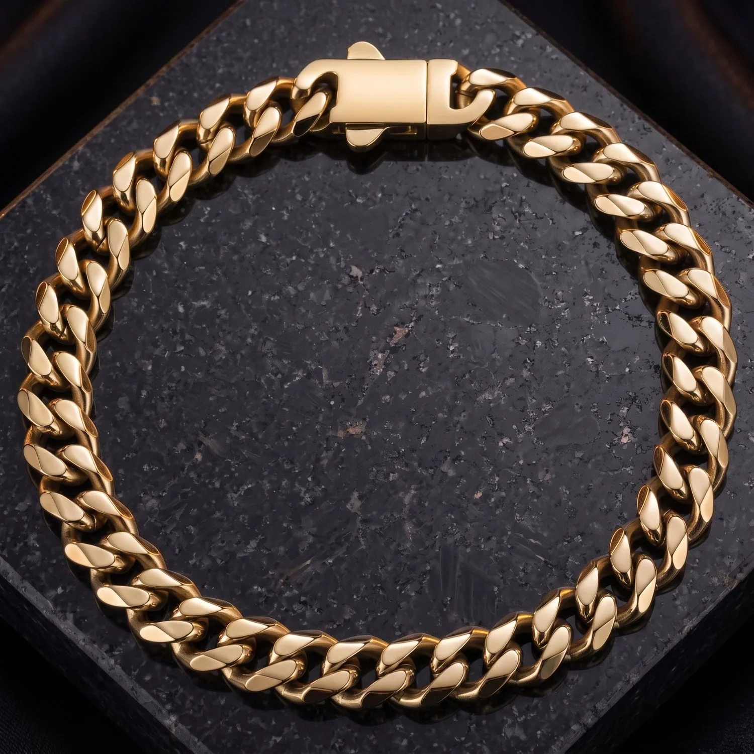 A heavy men's gold Cuban link bracelet featuring a modern rectangle box clasp, displayed flat on a dark polished granite background.