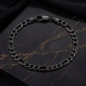 A black figaro chain bracelet laid flat on a dark marble surface with gold veins.