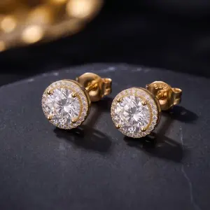 A pair of elegant yellow gold halo stud earrings with a round brilliant-cut center gemstone surrounded by a border of petite accent crystals, displayed on dark granite.