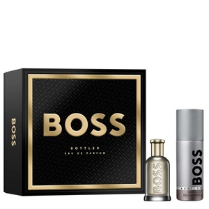BOSS Bottled fragrance gift set featuring a matte black and gold-framed box, a grey glass perfume bottle, and a matching metallic silver deodorant spray can.